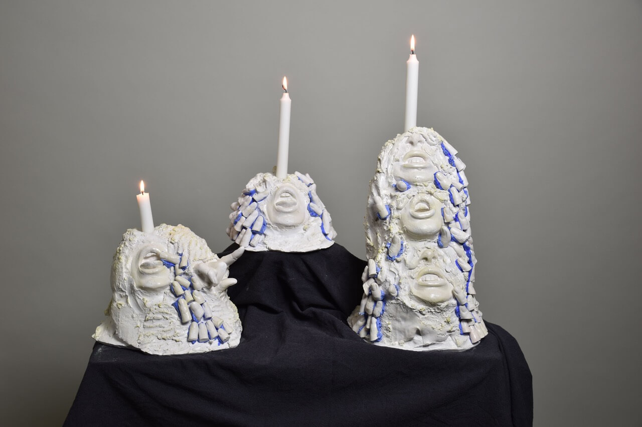 abstract candle holders with open mouths, hands and fingers on it